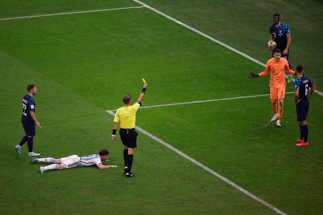 El árbitro italiano Daniele Orsato muestra tarjeta amarilla al meta croata Dominik Livakovic tras señalar penalti a favor de Argentina. EFE/ Alberto Estevez